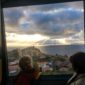 Two children looking out a window at the ocean.