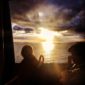 Two people sitting on a boat watching the sunset.