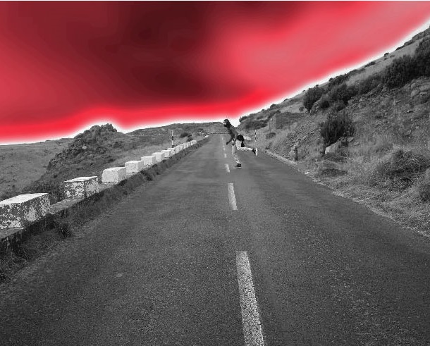 A black and white photo of a road with red sky in the background.