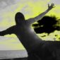 A man standing on the beach with his arms outstretched.